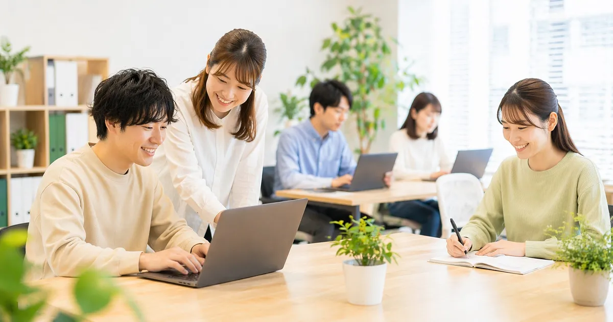 明るいオフィス環境で専門スタッフのサポートを受けながらPC作業に取り組む様子